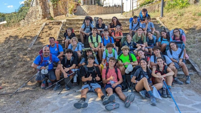 Eine Gruppe von Schülerinnen und Schülern des Colegio Esclavas sitzt auf Außentreppen vor einer Steinmauer mit Vegetation.