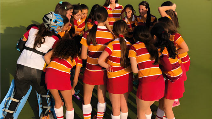 Eine Gruppe junger Frauen in gestreiften Uniformen steht auf einem Sportfeld auf dem Campus des Colegio San Gabriel.
