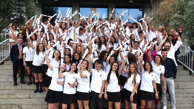 Eine Gruppe von Schülern der Colegio San Gabriel versammelt sich auf Außentreppen und hält verschiedene Fahnen und Banner hoch.