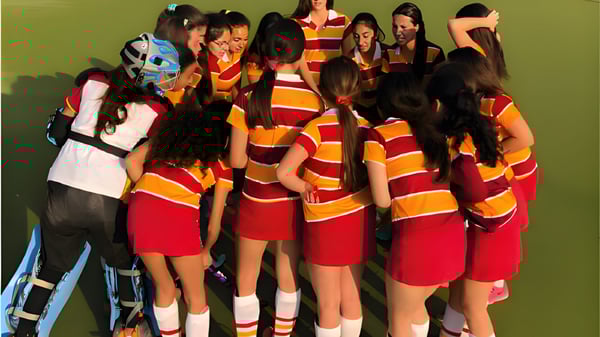 Eine Gruppe Schülerinnen des Colegio San Gabriel trägt bunte gestreifte Kleidung vor grünem Hintergrund.