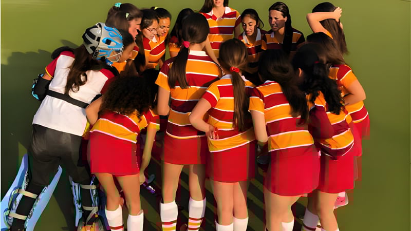 Eine Gruppe Schülerinnen des Colegio San Gabriel trägt bunte gestreifte Kleidung vor grünem Hintergrund.