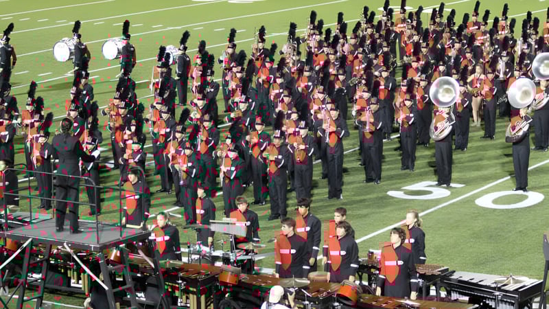 Die Marching Band von Collège Churchill High School spielt auf dem Footballfeld vor Zuschauern.