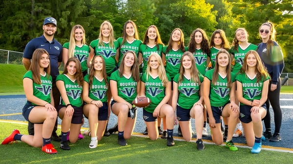 Eine Gruppe junger Athletinnen in grünen und blauen Uniformen auf dem Sportfeld des College Bourget.