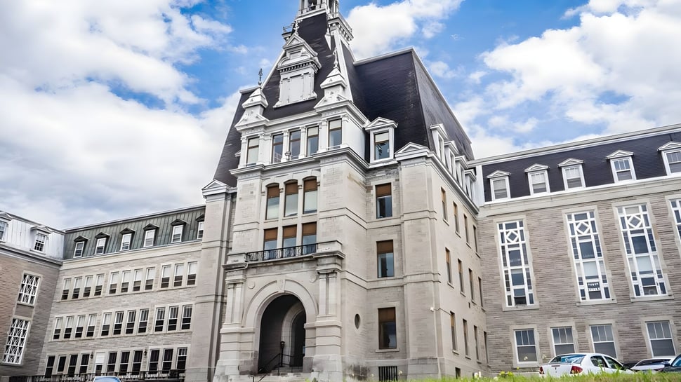 Das historische Hauptgebäude des College Bourget mit aufwändiger Steinarchitektur vor bewölktem Himmel in urbaner Umgebung.