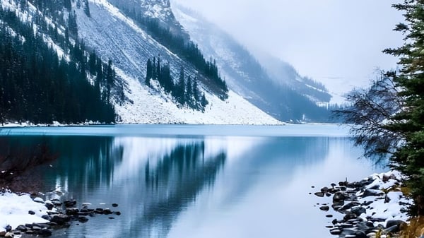 Schneebedeckte Berge spiegeln sich in einem ruhigen See mit türkisfarbenem Wasser auf dem Campus des College Bourget.