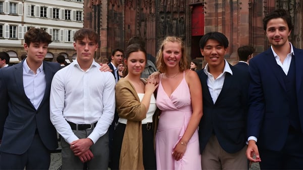 Eine Gruppe von Personen steht vor dem historischen Gebäude des Collège Episcopal Saint Étienne.
