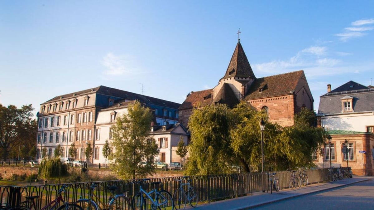Historische europäische Stadtstraße mit Kirchturm und verzierter Architektur vor dem Collège Episcopal Saint Étienne.