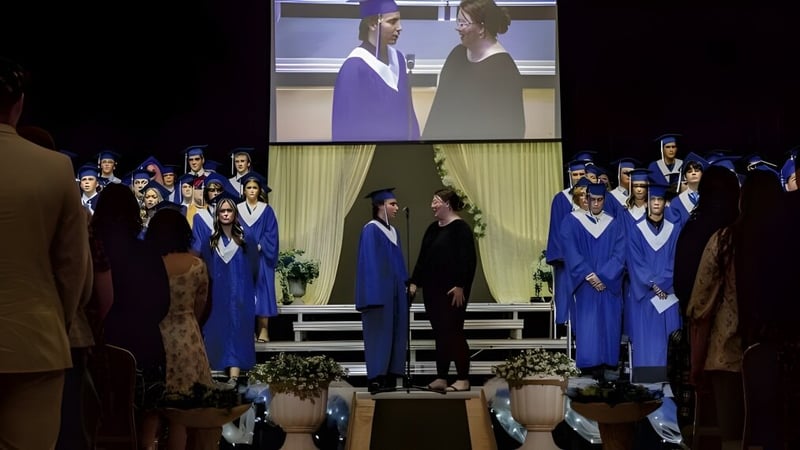 Schüler der College Heights Secondary School stehen bei der Abschlussfeier in blauen Talaren auf der Bühne.