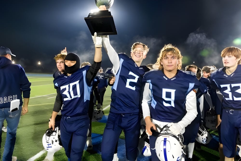 Die Footballspieler der College Heights Secondary School feiern ihren Sieg mit einem hochgehaltenen Pokal auf dem Spielfeld.
