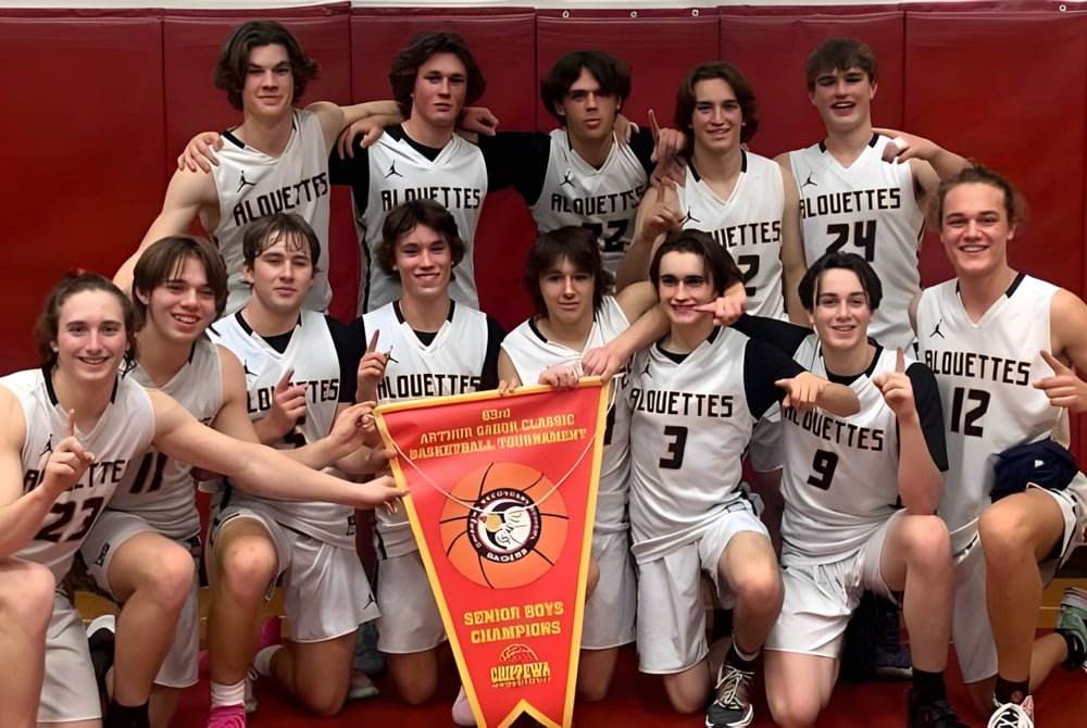 Eine Gruppe junger weiblicher Basketballspielerinnen des Collège Notre-Dame posiert gemeinsam mit einem Pokal vor rotem Hintergrund.