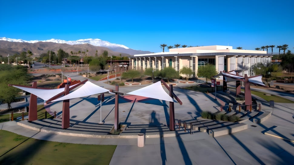 Das College of the Desert zeigt ein modernes Amphitheater im Freien mit bunten Sonnenschutzstrukturen vor grünen Bergen.