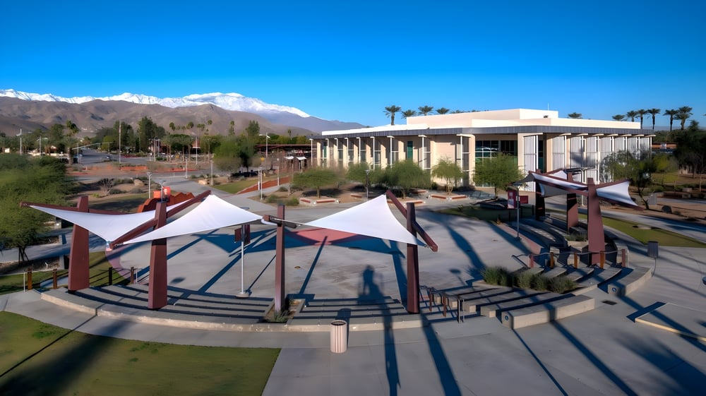 Das College of the Desert zeigt ein modernes Amphitheater im Freien mit bunten Sonnenschutzstrukturen vor grünen Bergen.