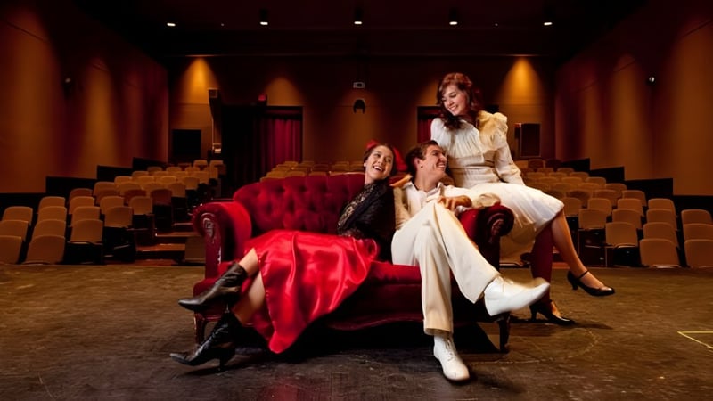 Eine Gruppe elegant gekleideter Frauen sitzt auf dem roten Samtsofa im Theater des College of the Desert.