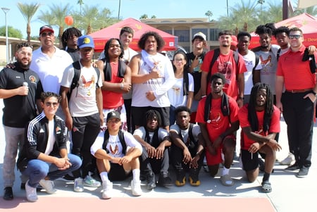 Eine Gruppe von Schülerinnen und Schülern mit Erwachsenen steht im Freien vor Palmen auf dem Campus der College of the Desert.