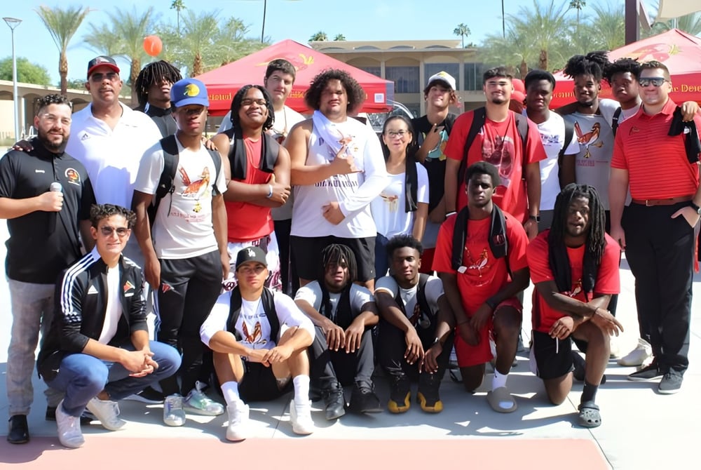 Eine Gruppe von Schülerinnen und Schülern mit Erwachsenen steht im Freien vor Palmen auf dem Campus der College of the Desert.