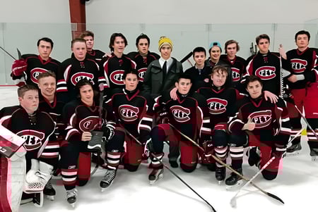 Eine Gruppe von Schülern des Collège Pierre-Elliott-Trudeau posiert auf einer Eisfläche in schwarzen und roten Hockeytrikots.