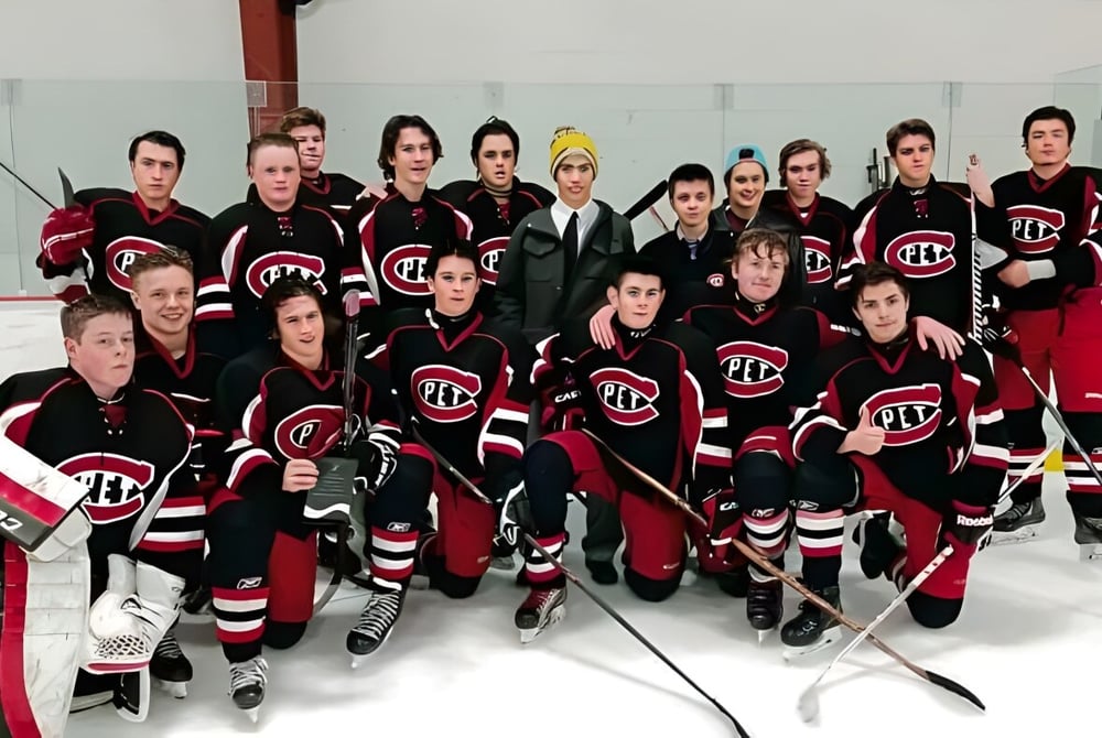 Eine Gruppe von Schülern des Collège Pierre-Elliott-Trudeau posiert auf einer Eisfläche in schwarzen und roten Hockeytrikots.