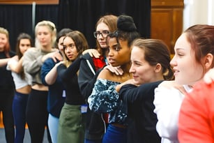 Schülerinnen und Schüler des College of Richard Collyer bei einer Probe vor einem dunklen Vorhang.