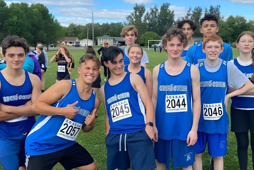 Eine Gruppe junger Athleten in blauen Uniformen steht auf dem Sportfeld des Collège Sacré-Coeur.