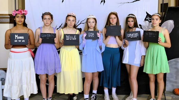 Eine Gruppe junger Frauen hält Schilder mit Texten vor einem abstrakten Muster auf dem Campus des Collège de Sainte-Anne-de-la-Pocatière.