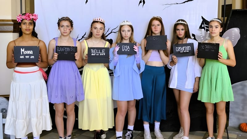 Eine Gruppe junger Frauen hält Schilder mit Texten vor einem abstrakten Muster auf dem Campus des Collège de Sainte-Anne-de-la-Pocatière.