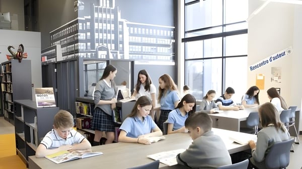Eine Gruppe Schülerinnen und Schüler arbeitet gemeinsam im hellen Klassenzimmer des Collège Sainte-Anne mit Blick auf die Stadt.