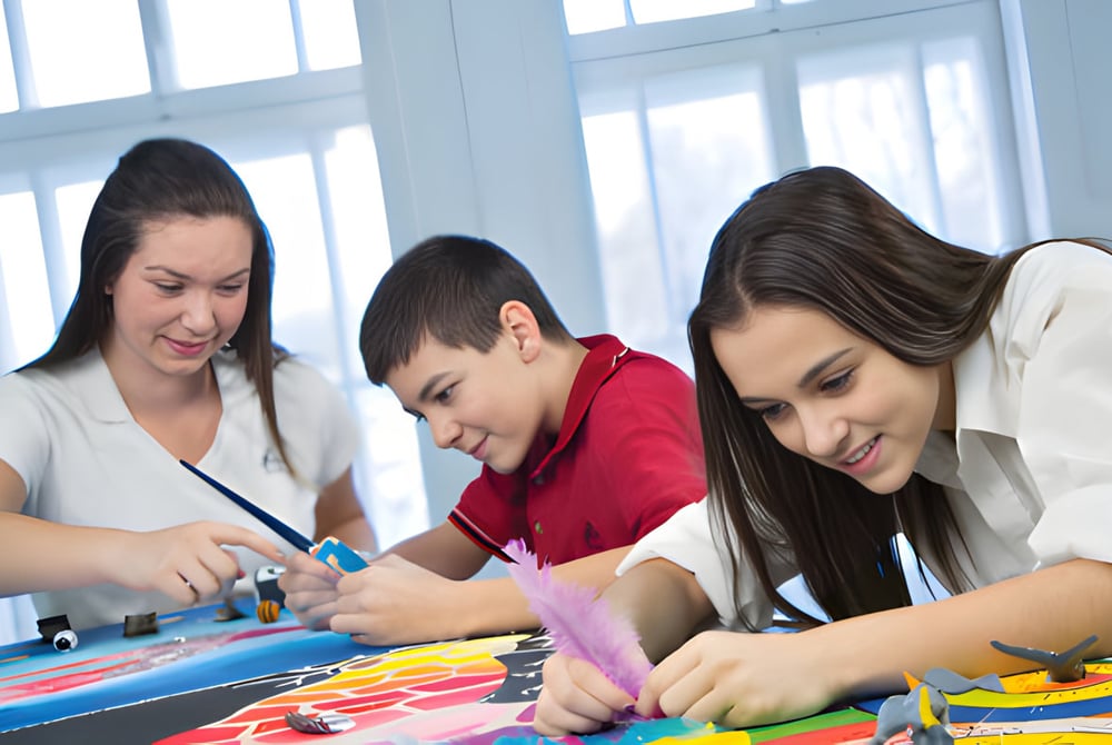 Schülerinnen und Schüler des Collège Sainte-Anne arbeiten gemeinsam an einem Kunstprojekt im hellen Klassenraum.
