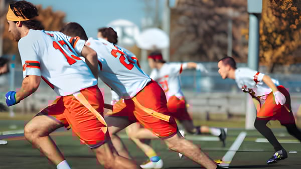Eine Gruppe Schüler von Collège Sainte-Anne spielt ein Mannschaftssportspiel auf einem Sportfeld in städtischer Umgebung.