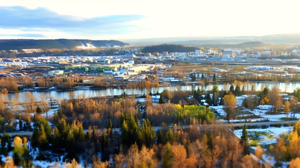 Luftaufnahme zeigt die Stadt mit schneebedeckten Bergen und einem See mit herbstlicher Vegetation nahe College Heights Secondary School.