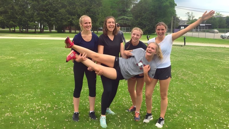 Eine Gruppe junger Schülerinnen steht lachend auf einer Grasfläche im Park auf dem Campus der Collingwood Collegiate Institute.