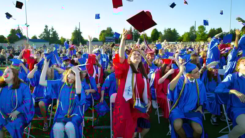 Schüler der Collège Churchill High School feiern ihre Abschlussfeier im Freien und werfen ihre Hüte in die Luft.