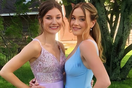 Zwei Schülerin stehen gemeinsam im grünen Außenbereich auf dem Campus der Colonel Gray High School.