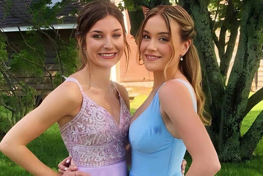 Zwei Schülerin stehen gemeinsam im grünen Außenbereich auf dem Campus der Colonel Gray High School.