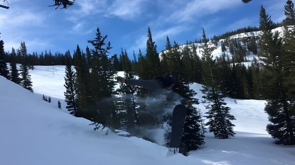 Ein Skifahrer fährt durch schneebedecktes Bergpanorama mit Kiefern im Vordergrund auf dem Gelände der Colorado Rocky Mountain School.
