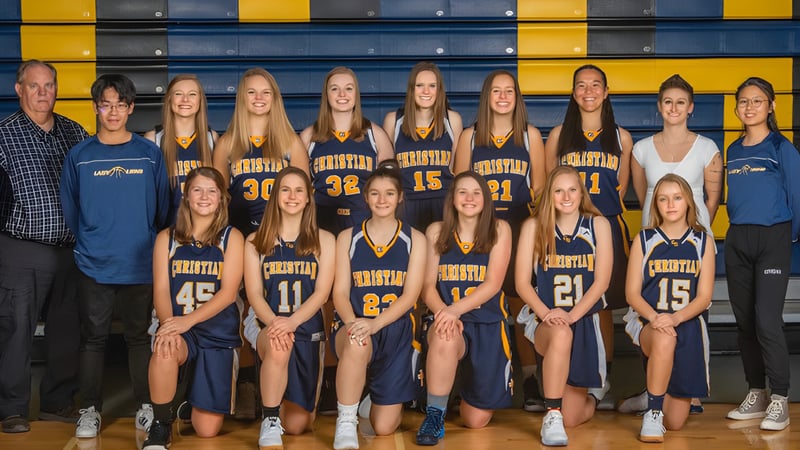 Eine Gruppe junger Basketballspielerinnen posiert vor buntem gelb-blauem Hintergrund auf dem Gelände der Colorado Springs Christian School.