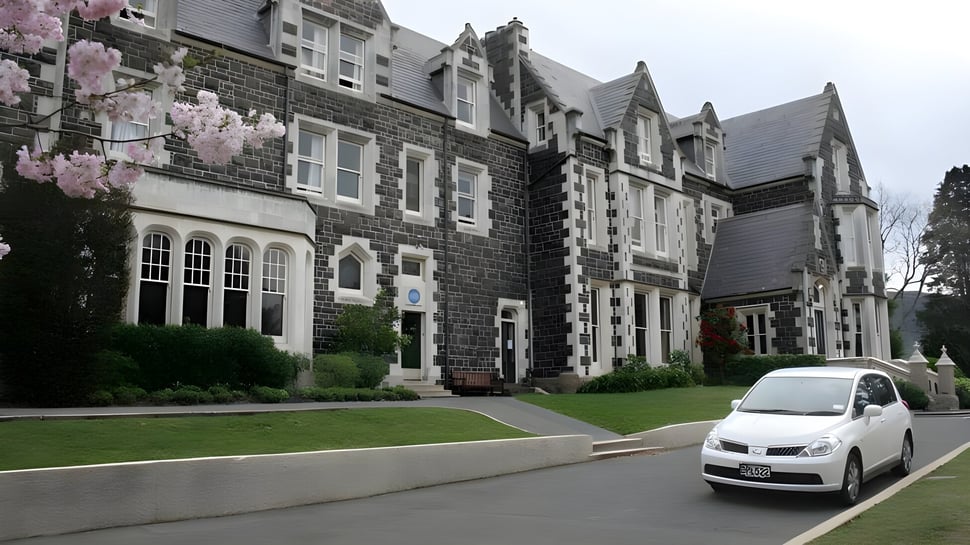 Das Columba College zeigt ein steinverkleidetes Gebäude mit aufwendiger Architektur und umgeben von Grünflächen.
