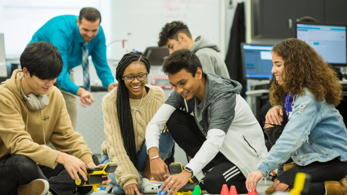 Eine Gruppe von Schülerinnen und Schülern des Columba College unterhält sich um einen Tisch im Klassenraum.