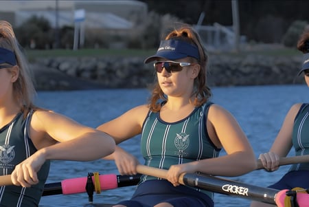 Drei Schülerinnen des Columba College stehen in Schwimmanzügen auf einem Steg vor einem Gewässer.
