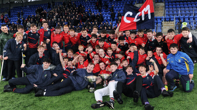 Schüler des Columba College feiern gemeinsam auf dem Sportfeld mit einer roten Fahne.