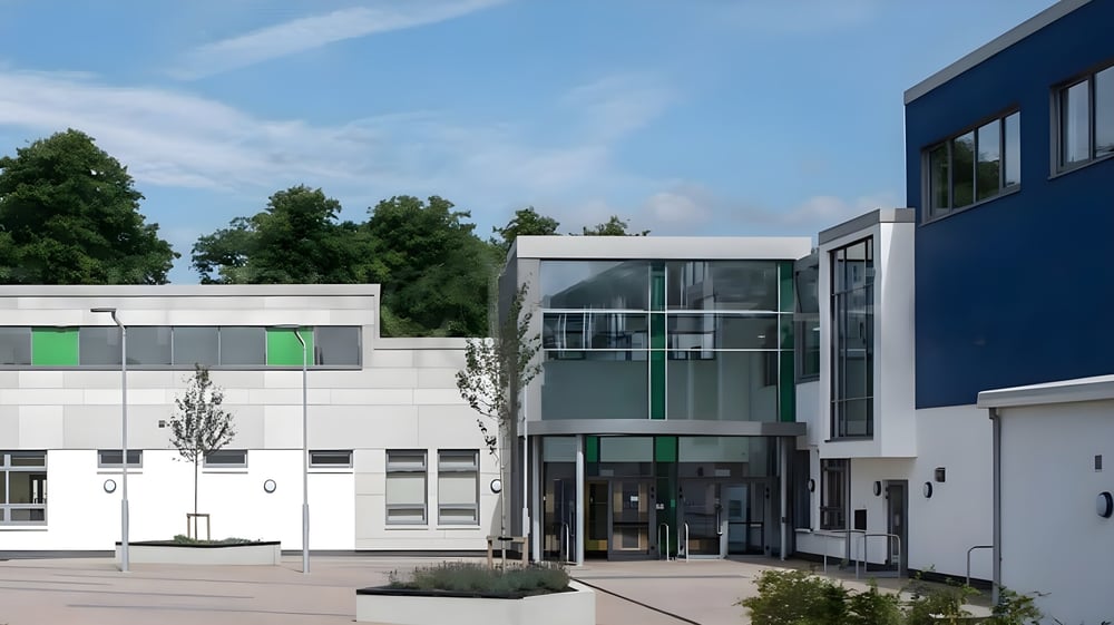 Das moderne mehrstöckige Gebäude mit gläsernem Eingang und grünen Akzenten auf dem Campus des Comeragh College.