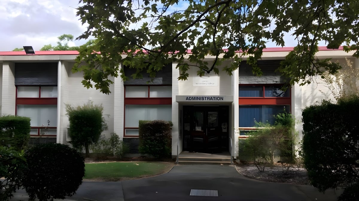 Das Verwaltungsgebäude mit rotem Dach und Eingangsbereich auf dem Campus des Como Secondary College ist von Bäumen umgeben.