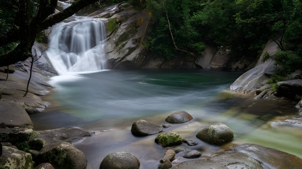 Ein Wasserfall fließt über felsiges Gelände inmitten grüner Natur ohne direkten Bezug zu Como Secondary College.