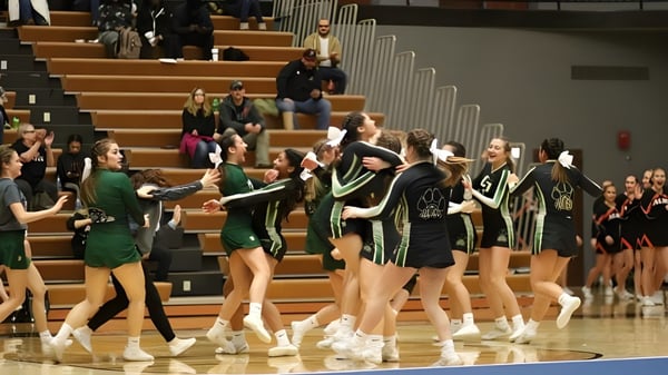 Eine Gruppe Cheerleader der Comstock Park High School führt auf dem Basketballfeld vor Zuschauern eine Performance auf.