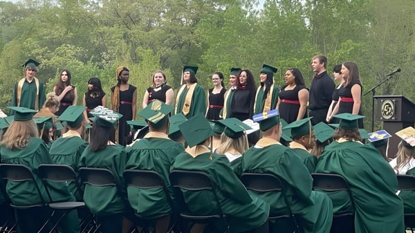 Eine Gruppe Abiturienten der Comstock Park High School steht draußen in grünen Talaren umgeben von Bäumen.