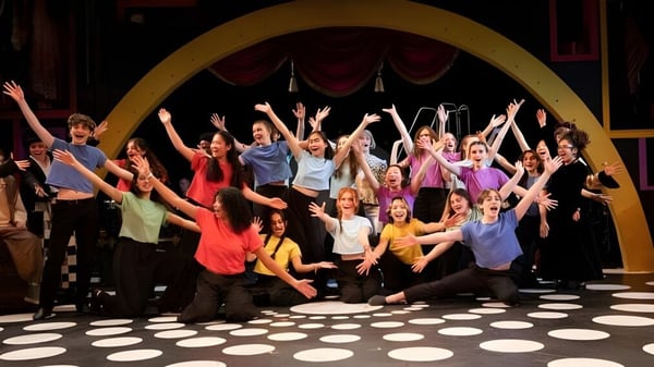 Eine Gruppe bunter gekleideter Schülerinnen und Schüler führt auf der Bühne der Concord Academy eine Performance vor einem großen Bogen auf.