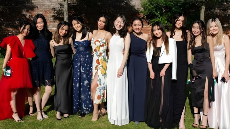 Eine Gruppe junger Frauen des Concord College posiert vor einer Backsteinmauer mit umgebendem Grün.