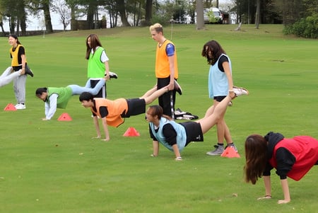 Schüler und Erwachsene des Concord College beteiligen sich an verschiedenen sportlichen Aktivitäten auf einem Rasenplatz mit Bäumen.