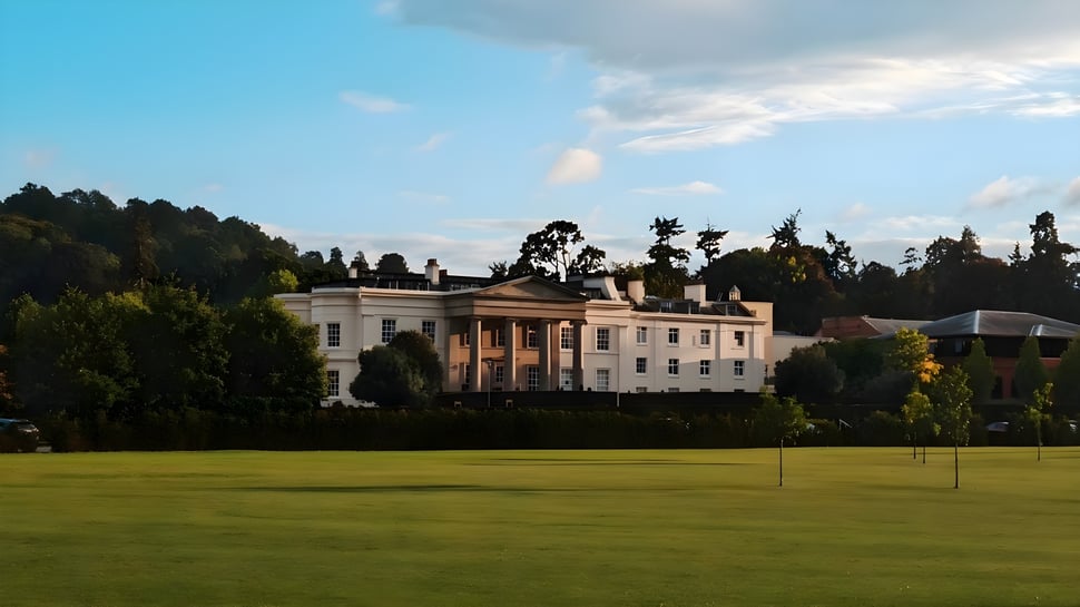 Das große weiße Herrenhaus mit gepflegtem Rasen und Bäumen im Hintergrund auf dem Campus des Concord College.