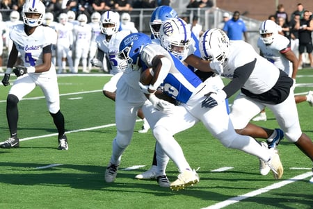 Ein Footballspiel mit Spielern der Conwell-Egan Catholic High School in weißen und blauen Trikots findet auf dem Spielfeld statt.