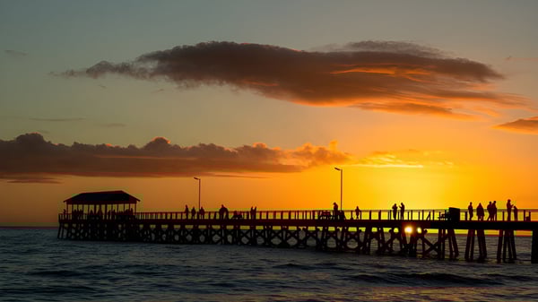 Ein Holzsteg erstreckt sich bei Sonnenuntergang mit dramatischen Wolken über dem Wasser auf dem Gelände der Coolum State High School.